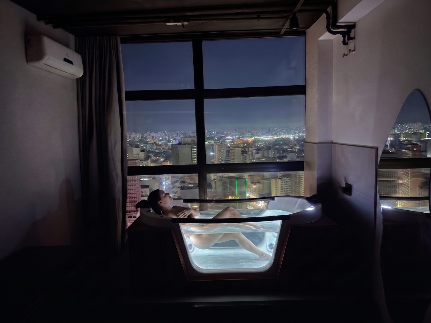 Suíte Jacuzzi Vidro com jacuzzi de fundo de vidro e vista noturna de São Paulo